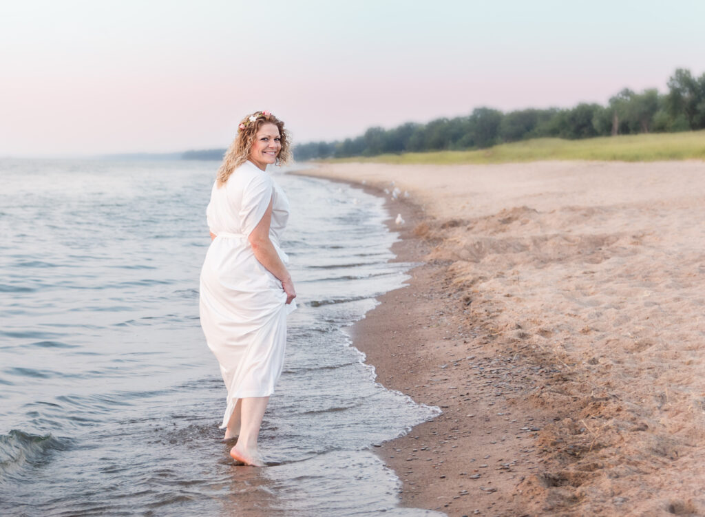 Woman walking barefoot along the shore at sunset