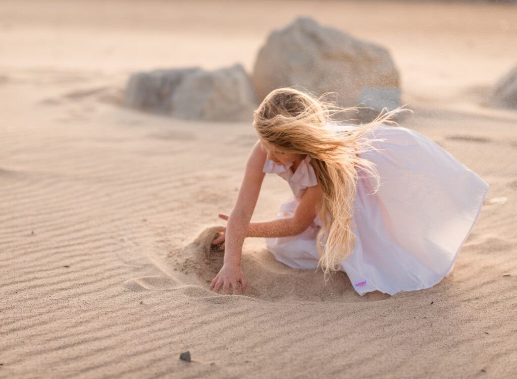 Young girl playing in the sand at the beach portrait
