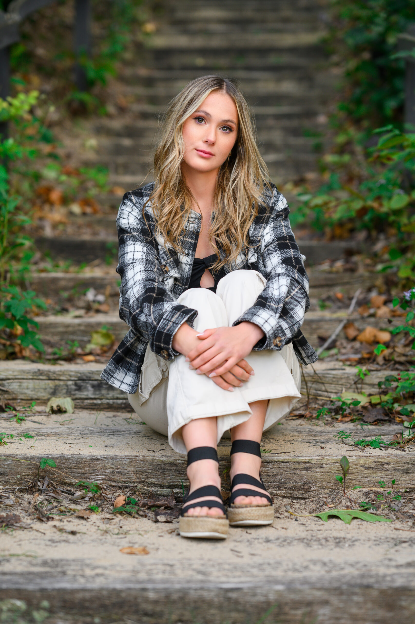 cozy fall senior girl sitting on beach stairs at warren dunes wearing cute plad top and sandals