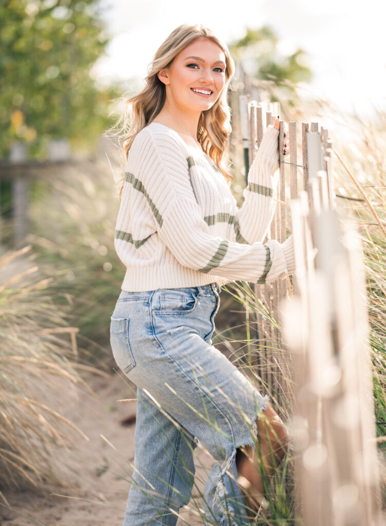 Young woman leaning against a wooden fence on the beach
