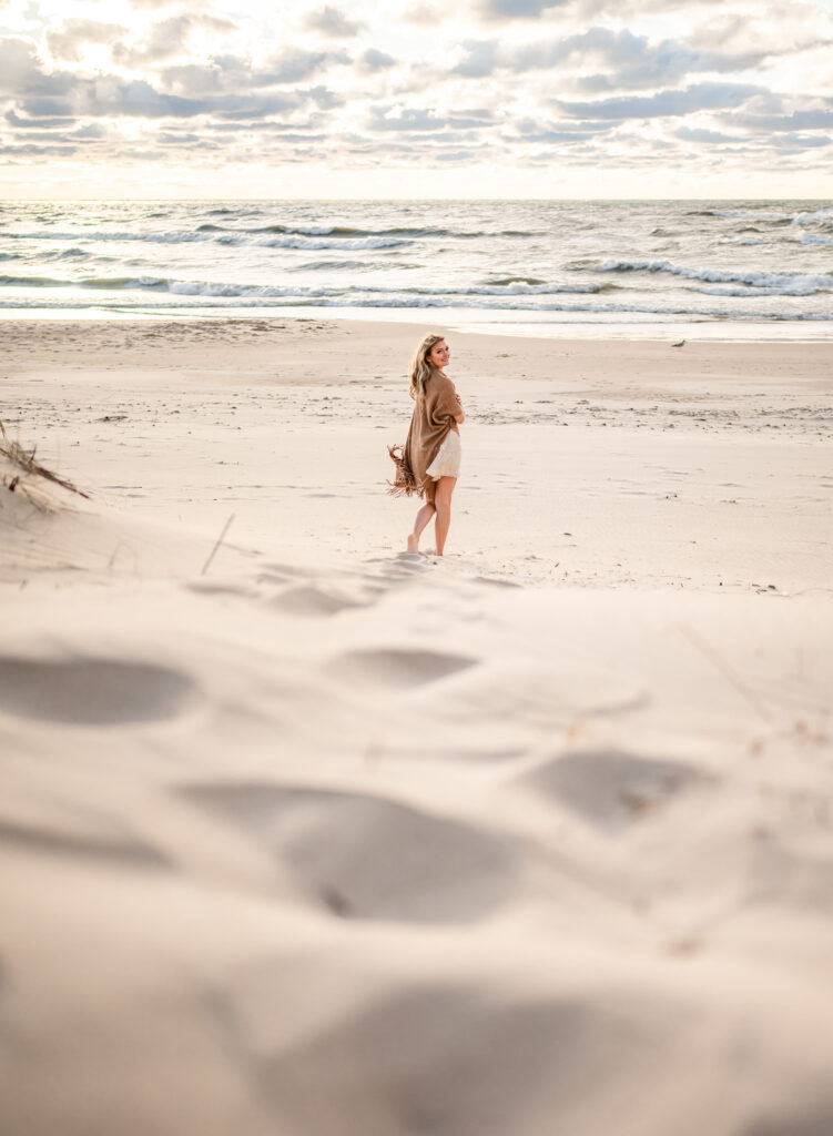 Lady walking barefoot across the sand by the sea