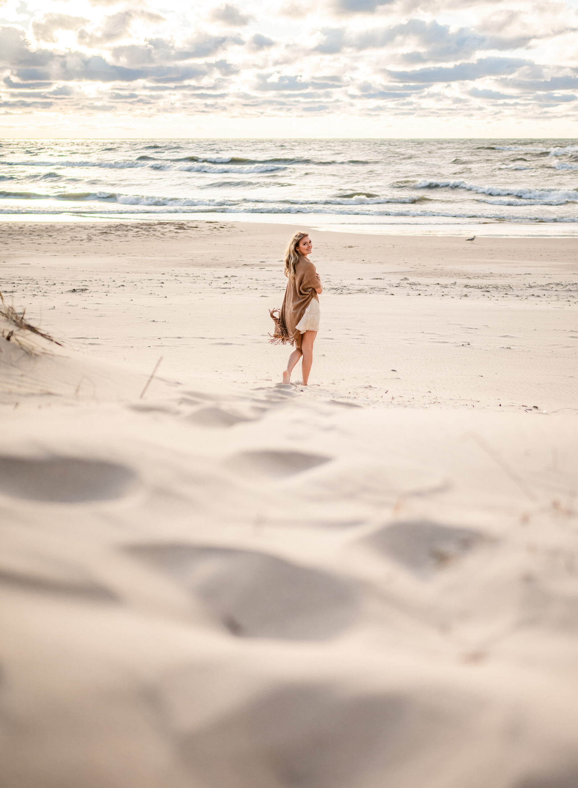 beautiful beach landscape at golden hour with girl looking back at photographer the waves beyond her | photographed by Leslie Q Photography | south bend photographer